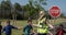 Woman with Hi-vest holding stop sign while group of kids cross the road