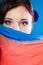 Woman hides her face with shawl on blue