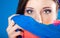 Woman hides her face with shawl on blue