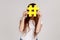 Woman hiding behind yellow hashtag symbol, covering face with hash sign, viral topics on internet.