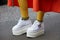 Woman with high wedge heel white sneakers shoes and orange skirt before Antonio Marras fashion show, Milan