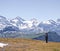 Woman hiker with backpack hiking on plateau with high altitude mountains in the background.