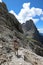 Woman hiker with backpack on shoulders walks on stone path in hi