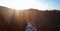 Woman hiker with backpack is sitting on edge of slope and enjoying a beautiful morning landscape with cliff and pine