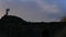 Woman hiker climbing hill on rugged rocky landscape