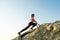 Woman hiker climbing steep big rock on a sunny day. Young female climber overcomes difficult climbing route. Active recreation in