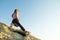 Woman hiker climbing steep big rock on a sunny day. Young female climber overcomes difficult climbing route. Active recreation in