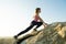 Woman hiker climbing steep big rock on a sunny day. Young female climber overcomes difficult climbing route. Active recreation in