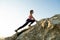 Woman hiker climbing steep big rock on a sunny day. Young female climber overcomes difficult climbing route. Active recreation in