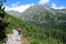 Woman hiker climbs a stone trail up to the top of mountain in High Tatras