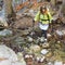 A Woman Hiker Crosses a Forest Creek