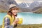 Woman hiker eats lunch and enjoys a view of the blue lake in the mountains, camping food concept