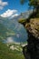 Woman hiker enjoying scenic landscapes at a cliff edge, Geirangerfjord