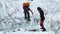 A woman hiker with a large backpack jumps over the icy river dividing the Miley Glacier.