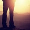 Woman hiker legs in tourist boots stand on mountain rocky peak. Sunny day