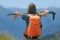 Woman hiker on mountain top with backpack and trekking poles, selective focus rear view, alps in background, summer fitness