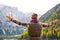 Woman hiker opening arms in joy against autumn background