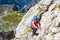 Woman hiker scrambling on a route in Mangart Mangrt mountain, just above the Mangart Saddle/Mangart Pass in the Julian Alps