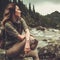 Woman hiker sitting on the stone near wild mountain river.