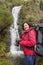 Woman hiker smiling and photographed waterfall.