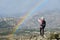 A woman hiker taking a picture of a rainbow while hiking in the mountains