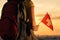 Woman hiker on the top of mountain in shorts and a t-shirt with a backpack and flag of Switzerland on a sunset sky background.