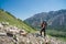 Woman Hiker trekking in mountains with child in backpack . Mother with baby boy travelling in summer sunny day.