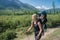 Woman Hiker trekking in mountains with child in backpack . Mother with baby boy travelling in summer sunny day.