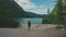 Woman hiker walking around the Braies lake and enjoys his spectacular sceneries, Dolomites, Italy