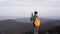 Woman hiker walking on edge of mountain ridge against background of sunset