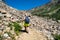 Woman hiker wearing a backpack and using trekking poles makes her way across scree along the Lake Solitude trail in Grand Teton