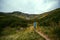 A woman hiker with a wide hat moves to the top of Spytsi mountain, Carpathians, Ukraine. He has a long stick in his hands. Travel