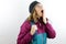 Woman hiker with wool cap and backpack looking amazed upwards holding her hand in front of her mouth