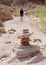 Woman Hikes Behind Cairn in Desert