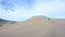 Woman Hikes Up Side of Sand Dune