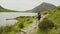 Woman hiking along idyllic shore of Llyn Idwal lake in mountains of Sn