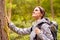 Woman Hiking Along Path Through Forest In Countryside Taking A Break And Resting Against Tree