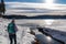 Woman with hiking backpack watching ducks on the frozen lake Forstsee, Techelsberg, Carinthia (Kaernten), Austria, Europe.