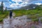 Woman hiking in the Colorado Rocky mountains, stream trail and mountain range in the background