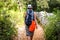 Woman hiking on country footpath with rock fence and woods.