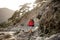 Woman with hiking equipment trekking through stoney coast