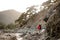Woman with hiking equipment treks through stoney coast