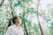 Woman hiking in forest nature wearing face mask while walking outdoors, looking up at trees in hope. Clean air