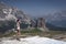 Woman hiking on snow field in front of Cinque Torri in the Dolomite Alps in summer, South Tyrol Italy