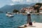 Woman hitchhiking on a pier. A girl is waiting for a boat on the pier