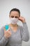 Woman hold blue sanitizer spray and fix face mask