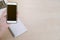 Woman hold cellphone and empty book and laptop on wooden table of brown