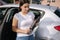 Woman hold portable vacuum cleaner in front of car. Attractive young woman prepare for cleaning in garage