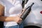 Woman hold portable vacuum cleaner in front of car. Attractive young woman prepare for cleaning in garage. Close-up of