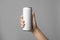 Woman holding aluminum can with beverage on grey background, closeup.